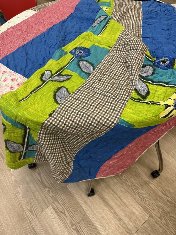 A quilt made of clothing scraps. There are many different colors and designs.