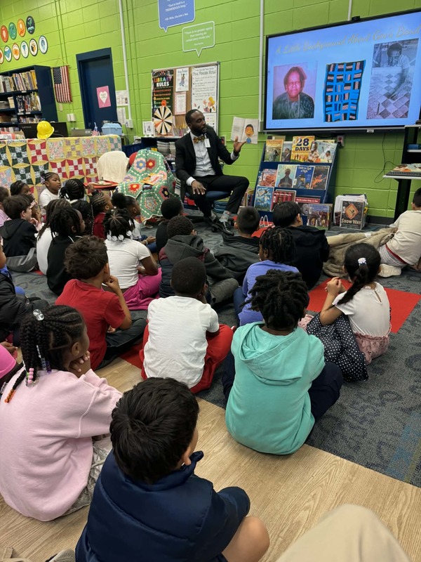 Mr. Saulsberry reading the book "Charles  and His Gee's Bend Quilt."