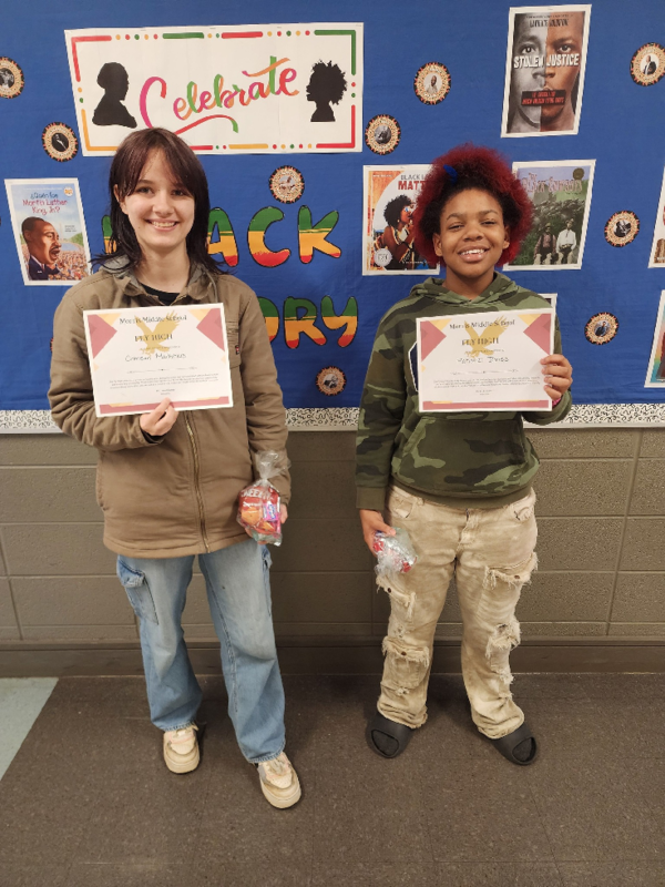 Two girls hold up their "Fly High Fridays" certificates.