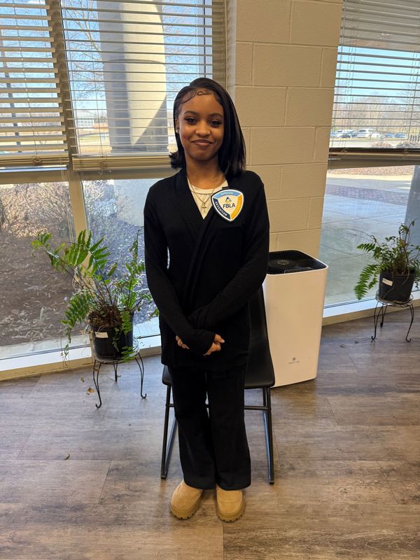 FBLA student standing in all black posing for picture with an FBLA button on her shirt
