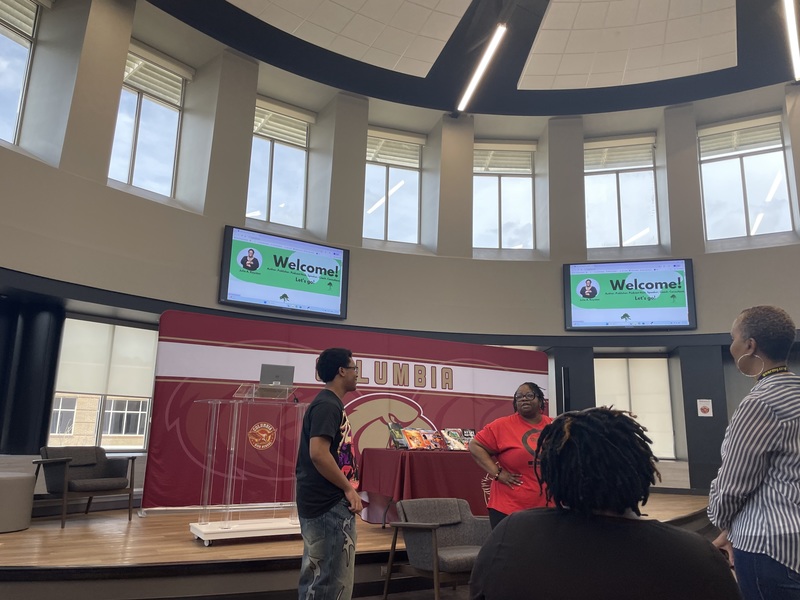 Student speaking to Dr. Royston while his mom and friend stand and sit in audience