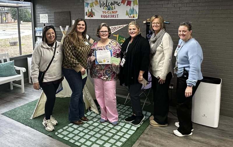 Ms. Hendley surrounded by leadership team and community members as she holds her award.