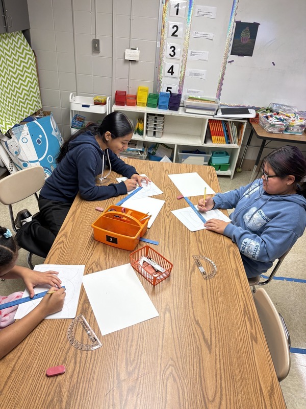 Fifth graders using rulers to make straight lines for their art projects in the art classroom.