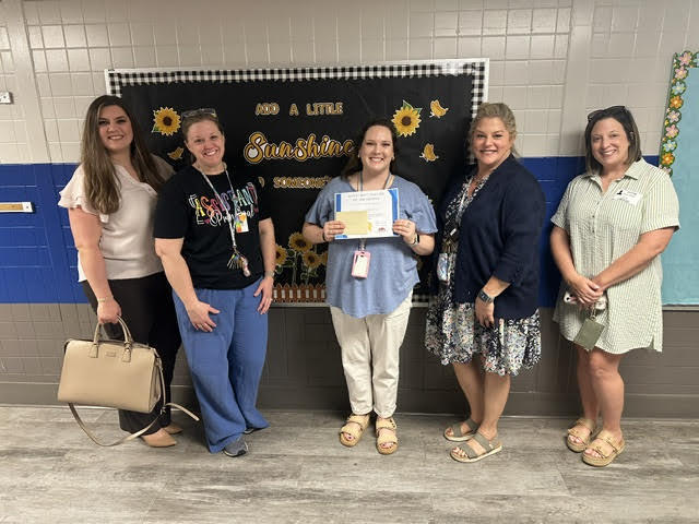 Ms. Howard receiving her certificate for Teacher of the Month with Administration and Community Members.