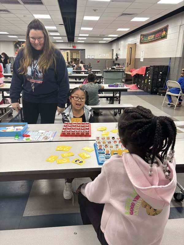 Ms. Fuller and two second graders playing Guess Who.