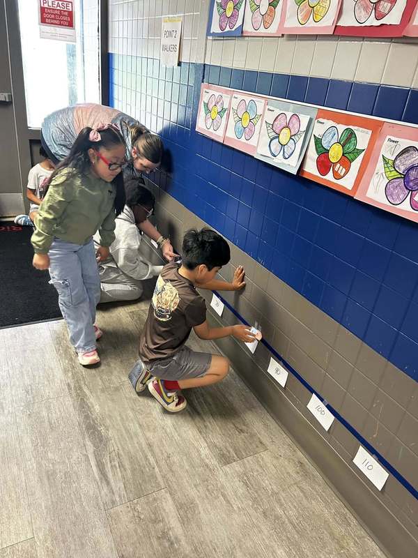 Ms. Fields and her students creating a math plot line in the hallway.