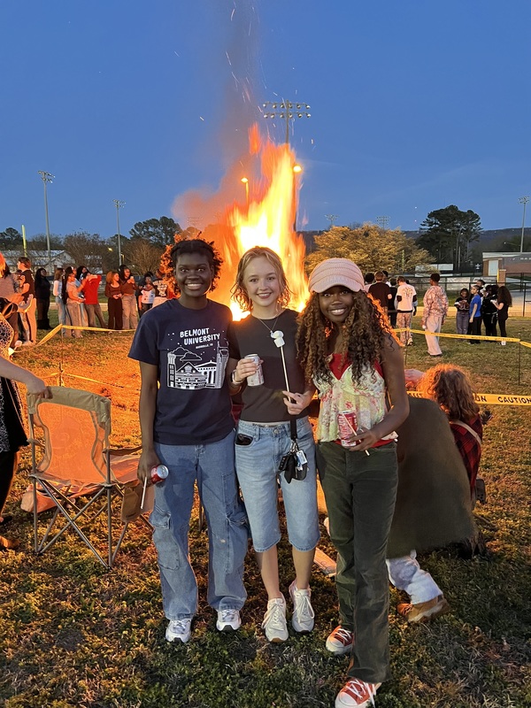 3 students pose with snacks in front of the bonfire at NCTHS.