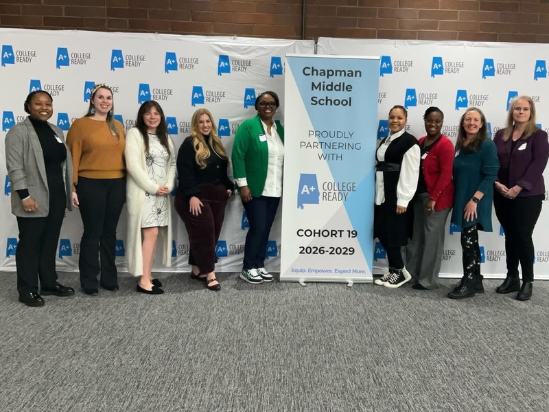 Chapman Middle school staff pose with district staff in front of the A+ College Ready Cohort 19 2026-2029 banner