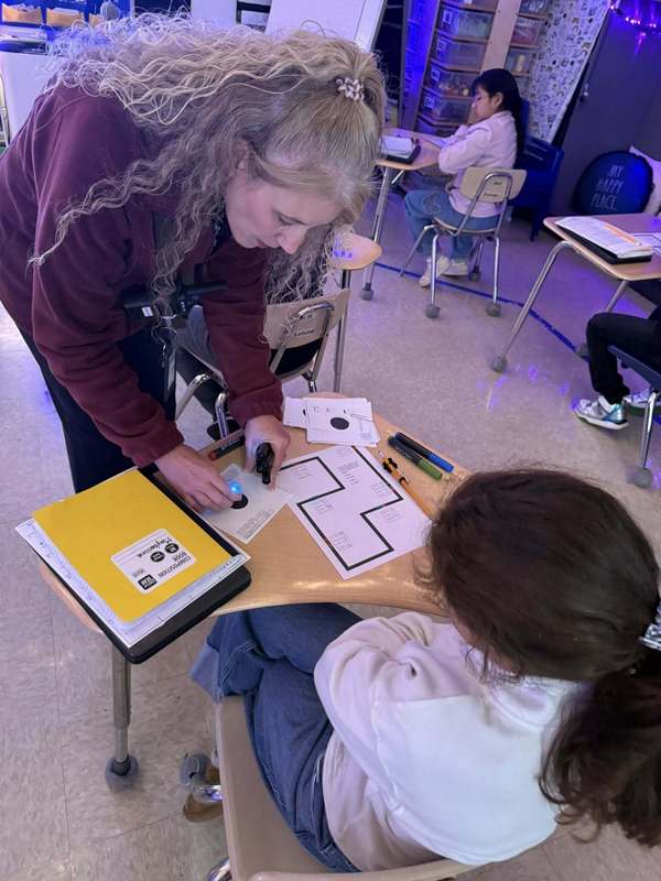 Mrs. Brooks showing a studen how to complete the Ozobot activity