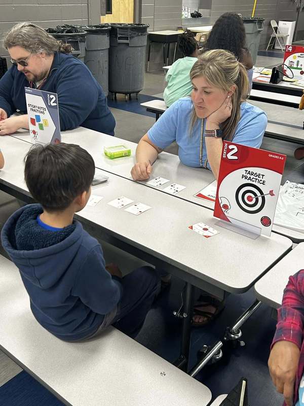 Mrs. Preston helping a student with a math game in the cafeteria