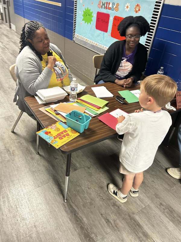 Ridgecrest PreK teachers helping a student with a literacy activity
