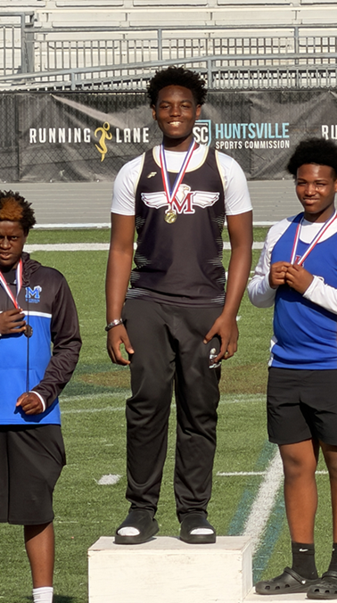 M Thompson stands on a podium wearing his medal