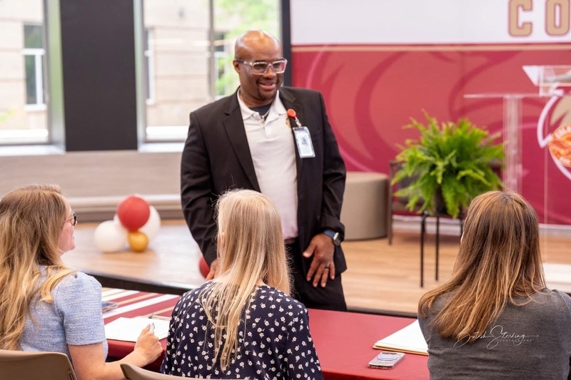 Dr. Richey standing in front of Judges table talking to three women sitting at table.