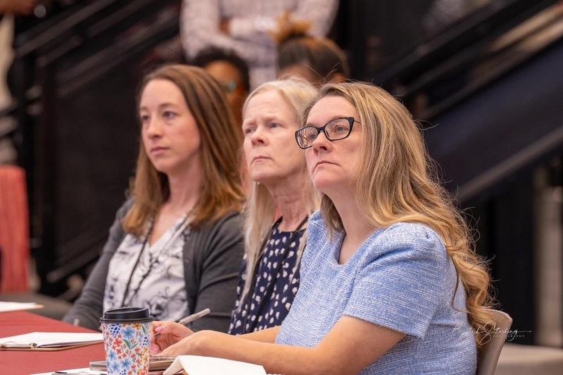 3 women sitting at table looking on