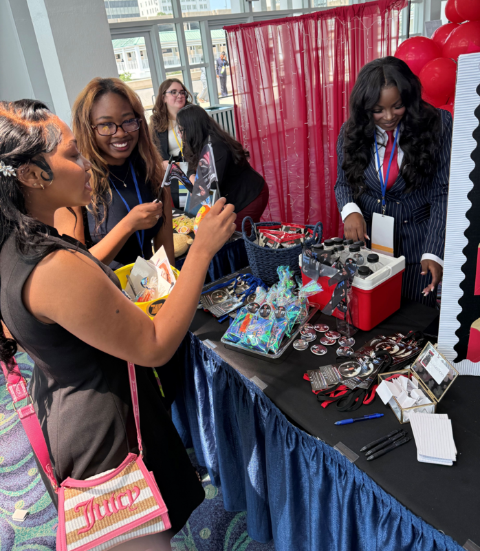 4 students from Future Business Leaders of America standing around a table looking and holding up items from the table.