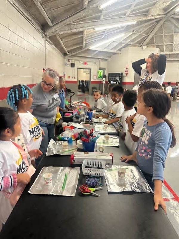 Second grade students trying to build something to protect their marshmallow at the "Peeps in Space" station.