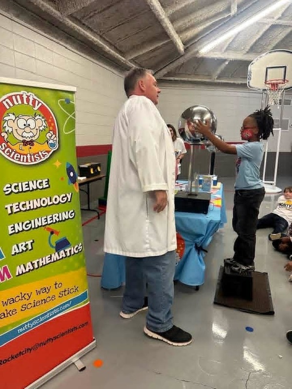 A third grade student putting his hands on the Van Da Graff Generator.