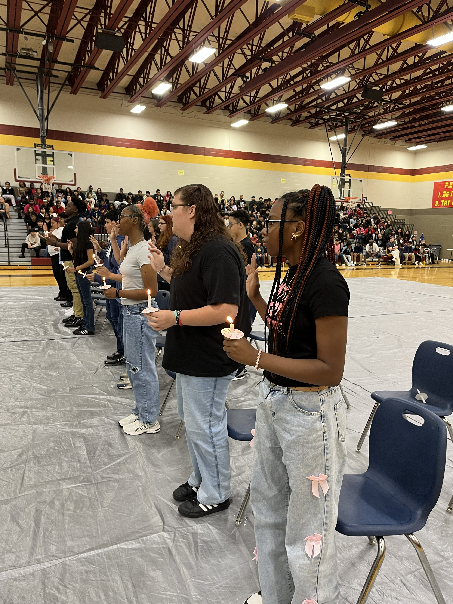 The new inductees to the NJHS stand and recite  their  pledge to the organizaton. Each student holds a lit candle in their left hand while they raise thei right hands for their pledge. 