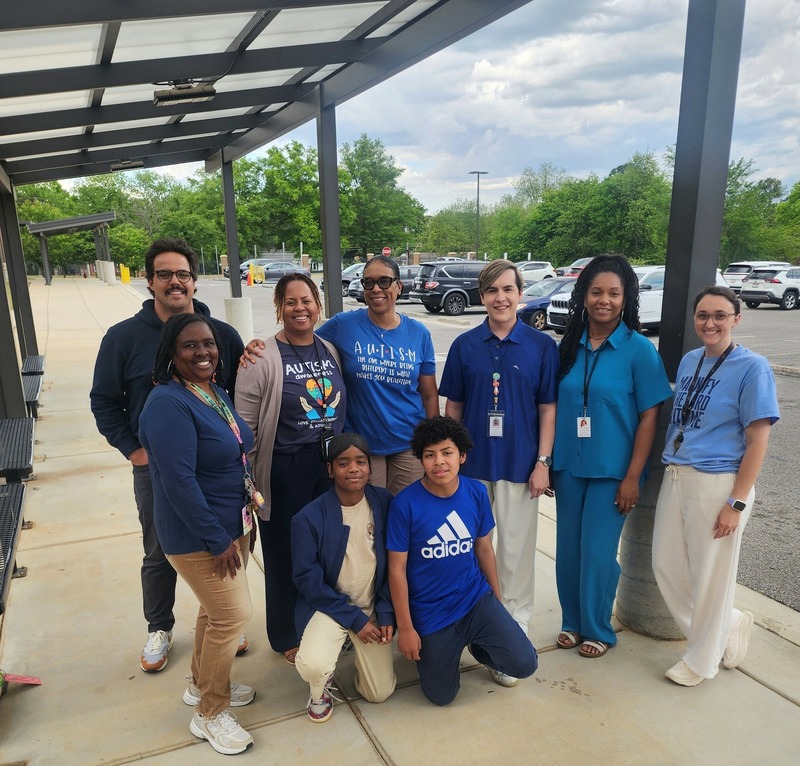 Seven teachers and two students pose in their blue shirts to support Autism and Child Abuse Awareness