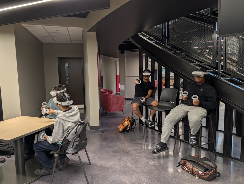 Students from Chemistry class sitting at able and on side in high top chairs using VR headsets for a lesson