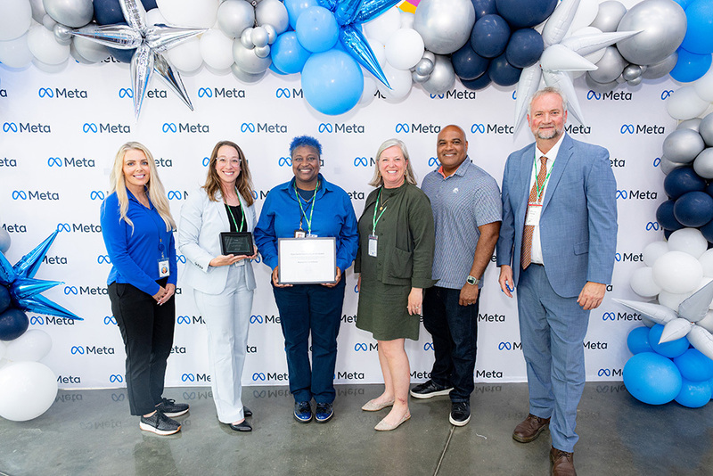 META employees posing with Rachel Evans, Bonnie Garrett, Elizabeth Fleming, and AJ Buckner to present the grant certificate