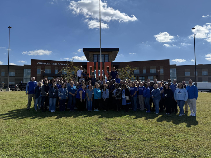 Grissom Highschool with the words "The Weekly Update". The staff is Standing in front of the school