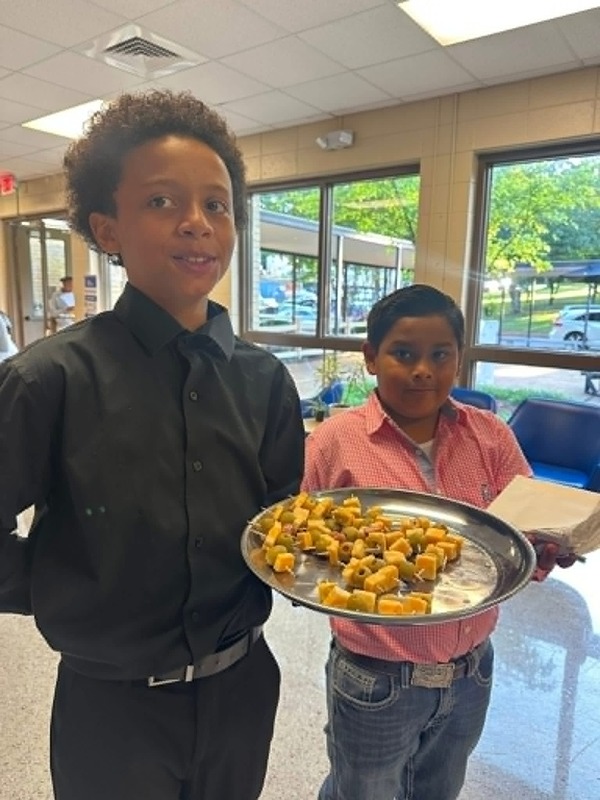 Students walking in the foyer serving hors d'oeuvres.