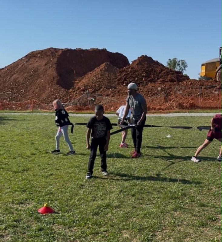 3rd grade students playing a single person 4-way tug of war .