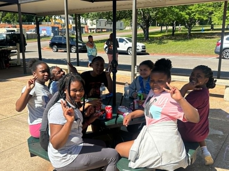 5th grade girls sitting and laughing while having their snack in the courtyard.