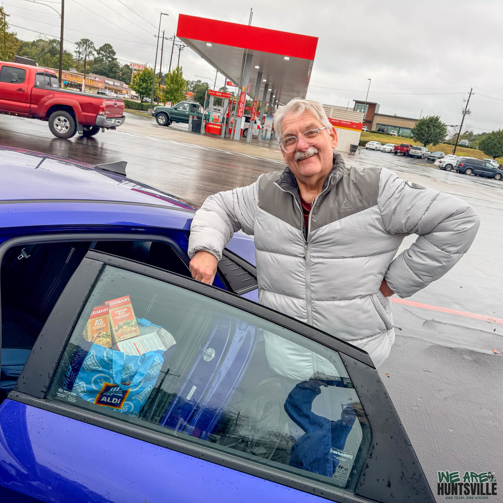 Man posing next to car getting donation