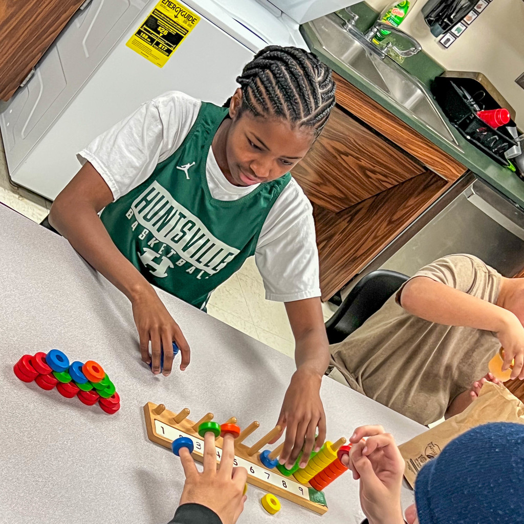 lady Hornet basket player playing with a student