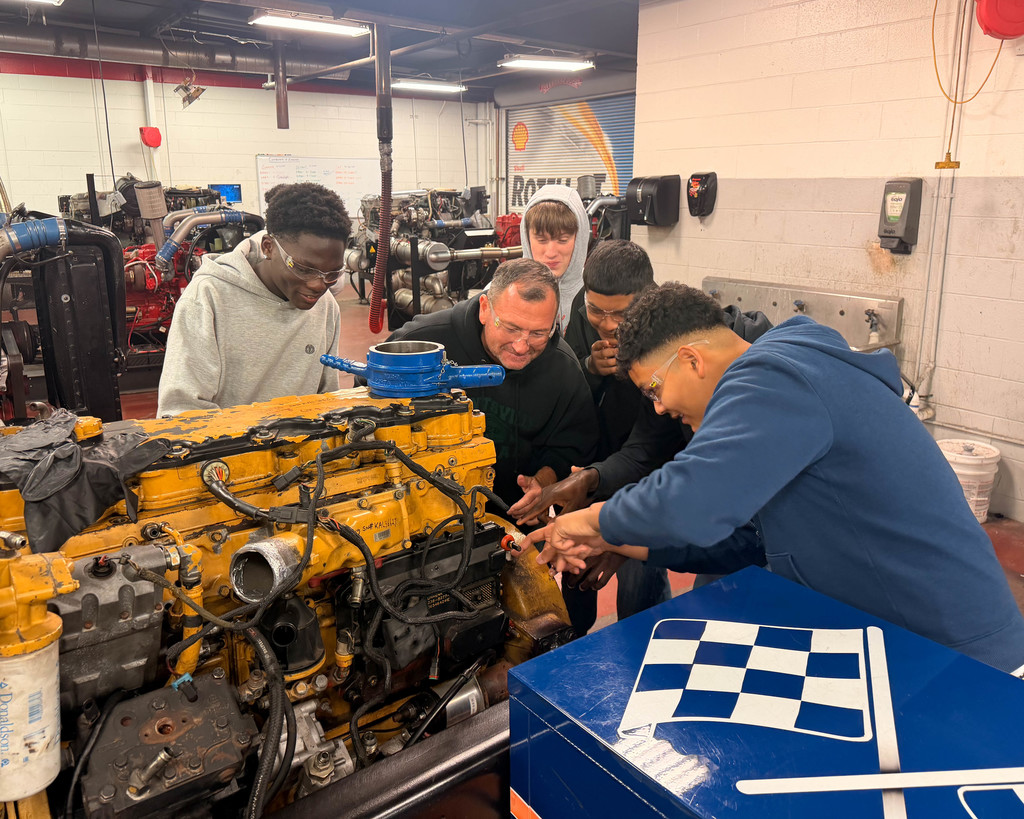 Teacher and students look at engine