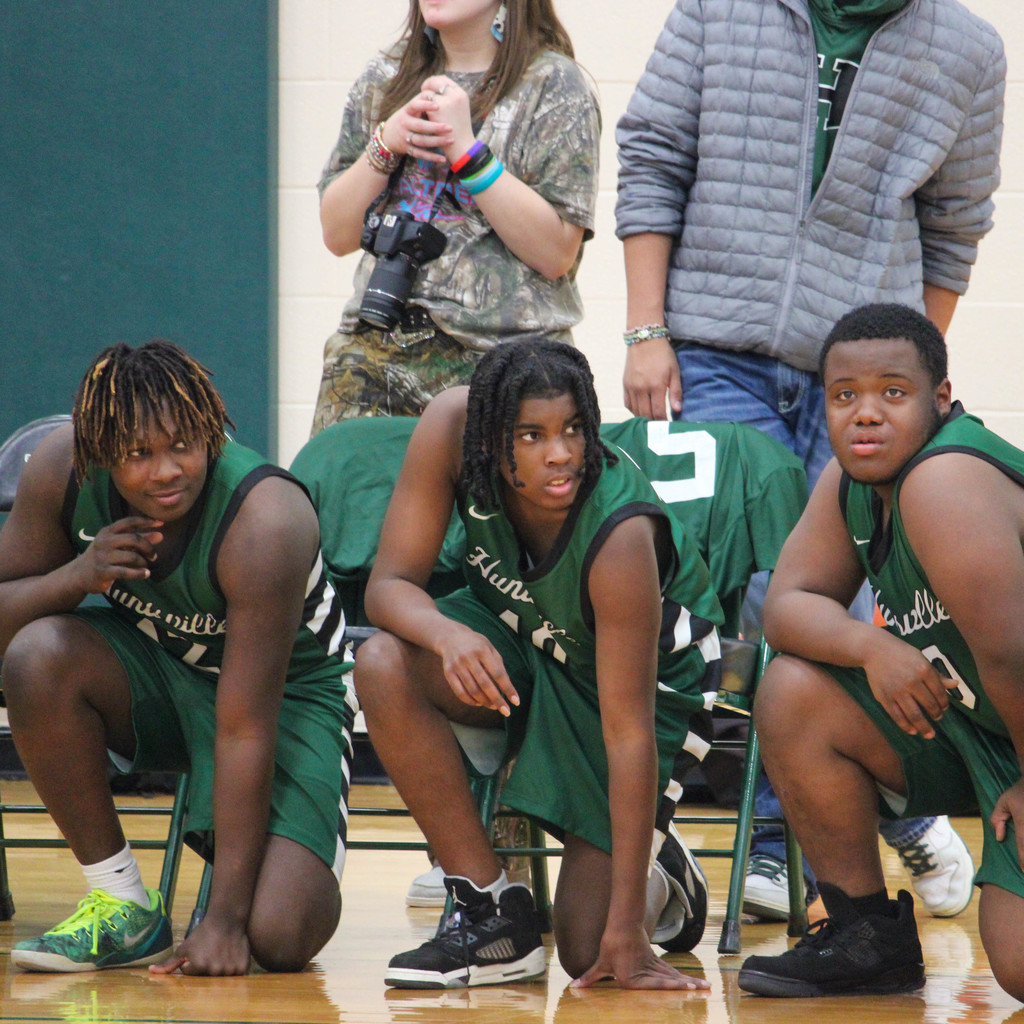 three players wait their turn to go into the game
