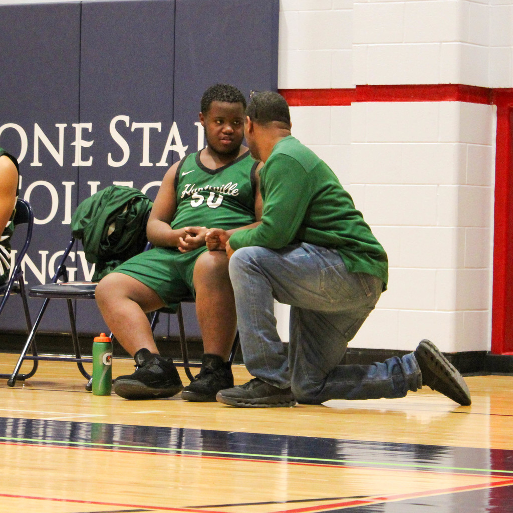 Coach with a heart to heart with student on bench