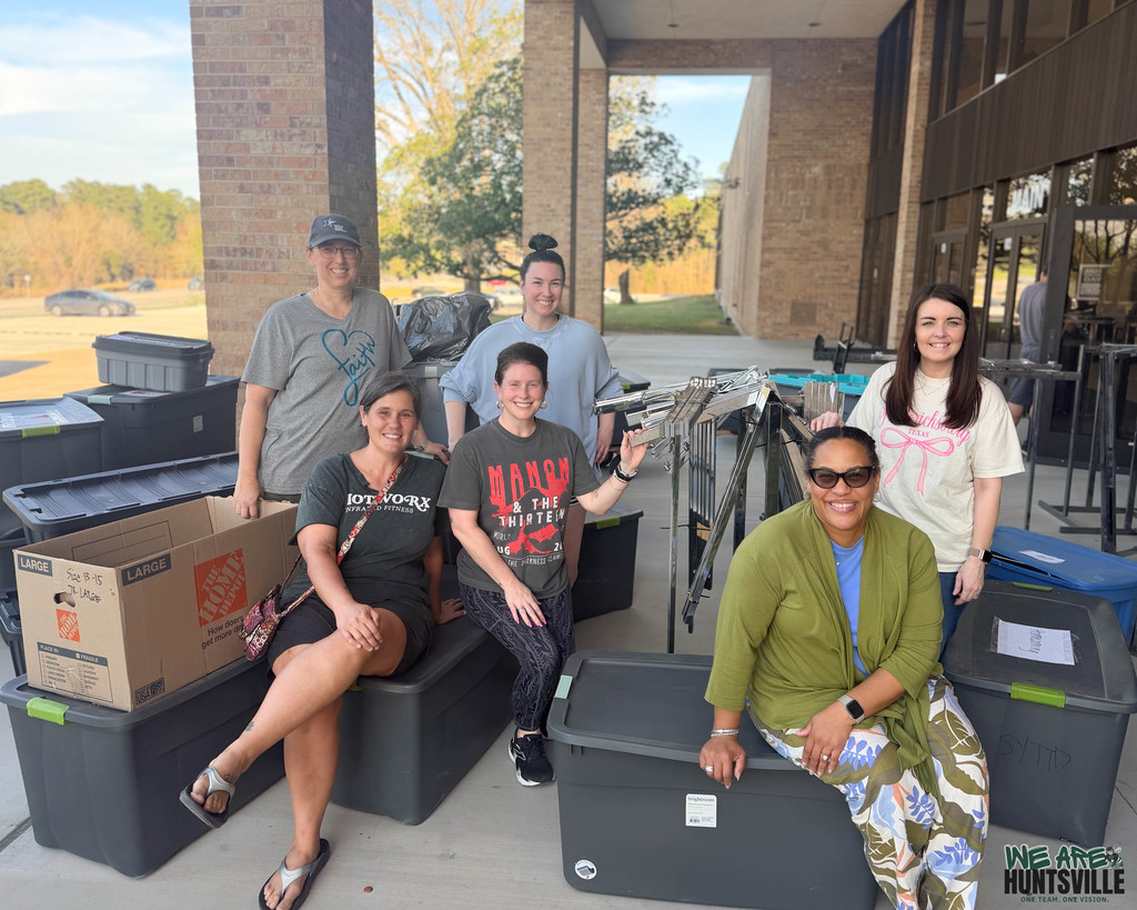 Junior Service League Ladies posing with all of the bins of dresses