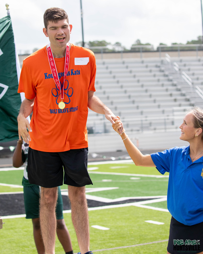 An athlete on the podium getting help with balance from student