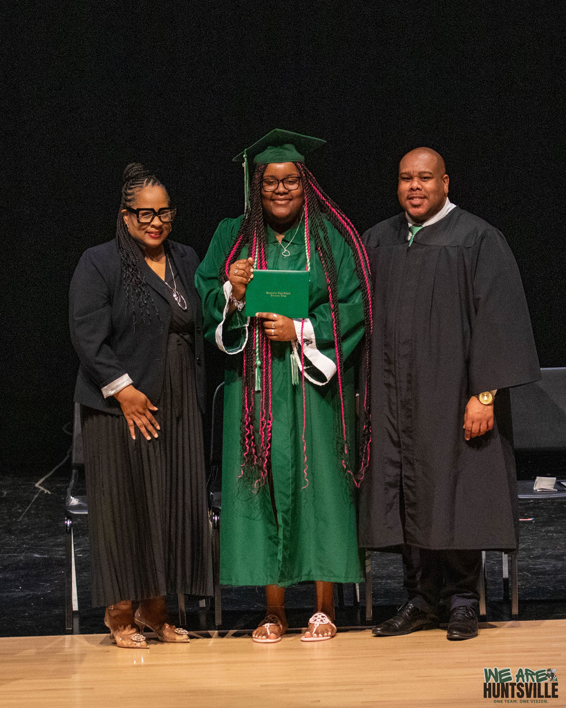 Proud Graduate poses between to principals