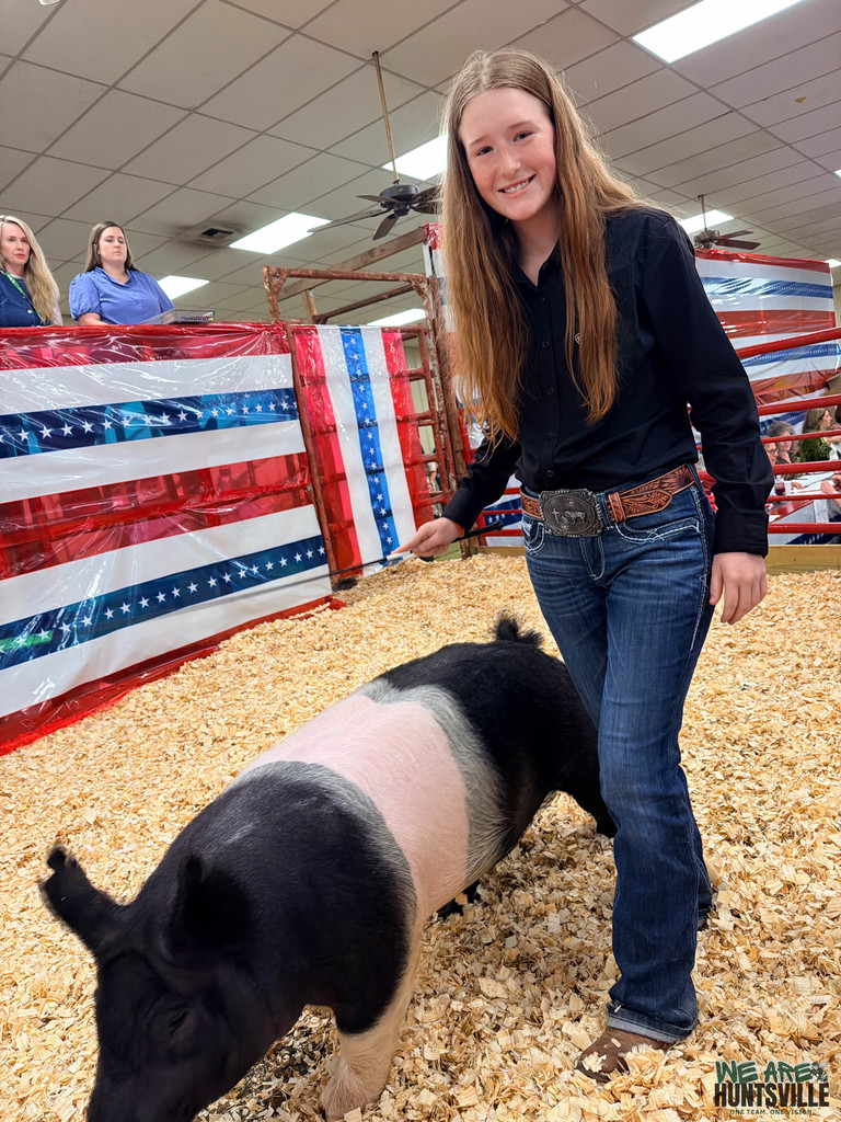 Youngish girl smiling with her pig at auction