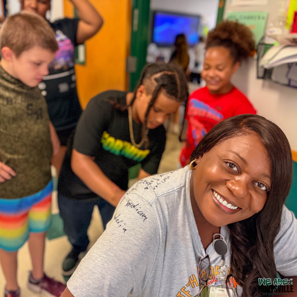A counselor leans forward to get her students to sign her shirt