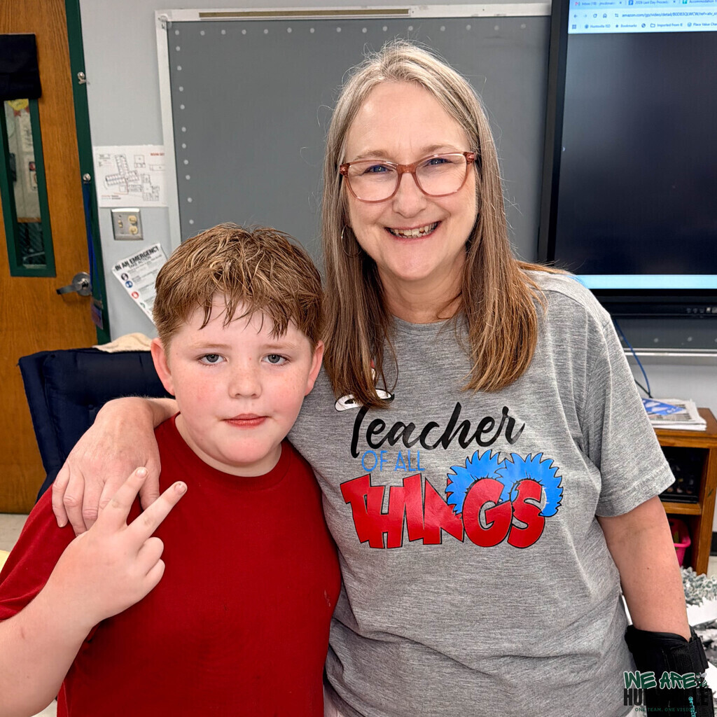 A boy student that poses seriously with his teacher