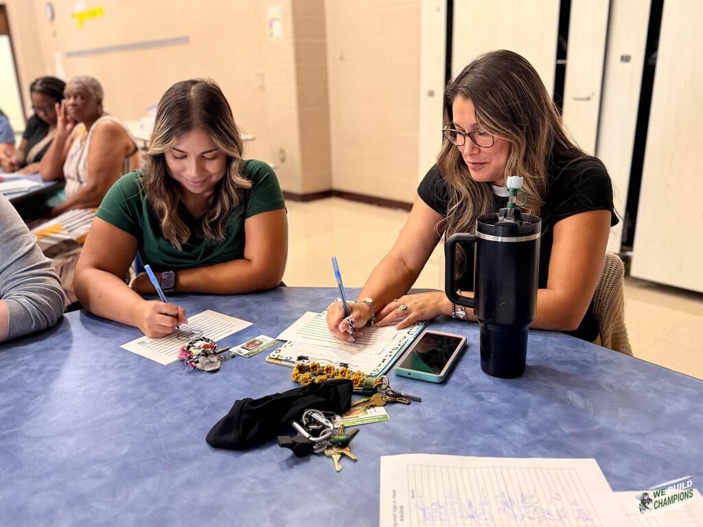 Two staff members filling out their cards