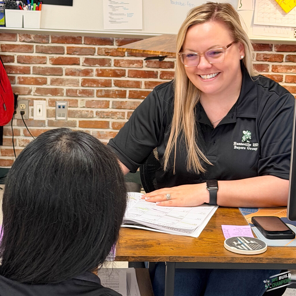 buyers group shirt wearer at desk talking to student