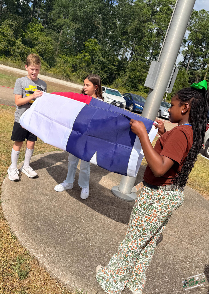 all three students holding flag