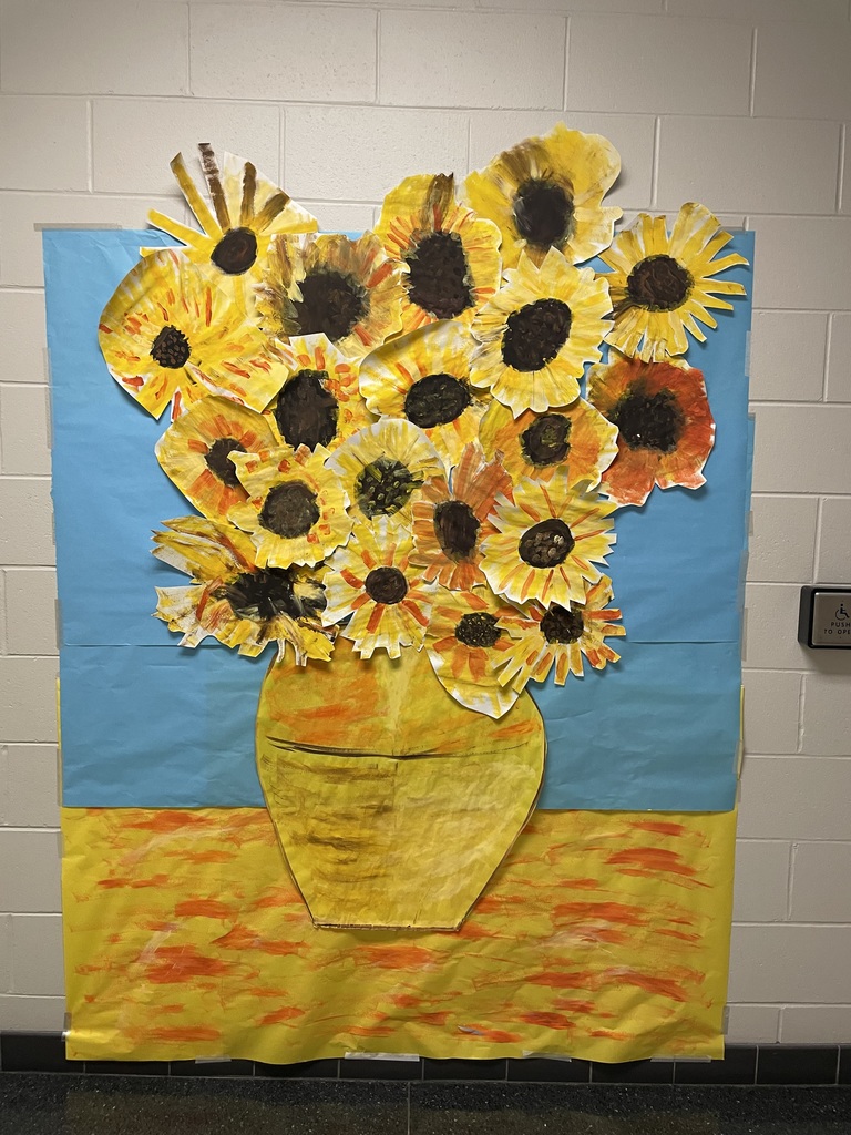 Collaborative student artwork showing a large bouquet of painted sunflowers in a yellow vase, inspired by Van Gogh’s style, displayed on a blue and yellow background in a school hallway.