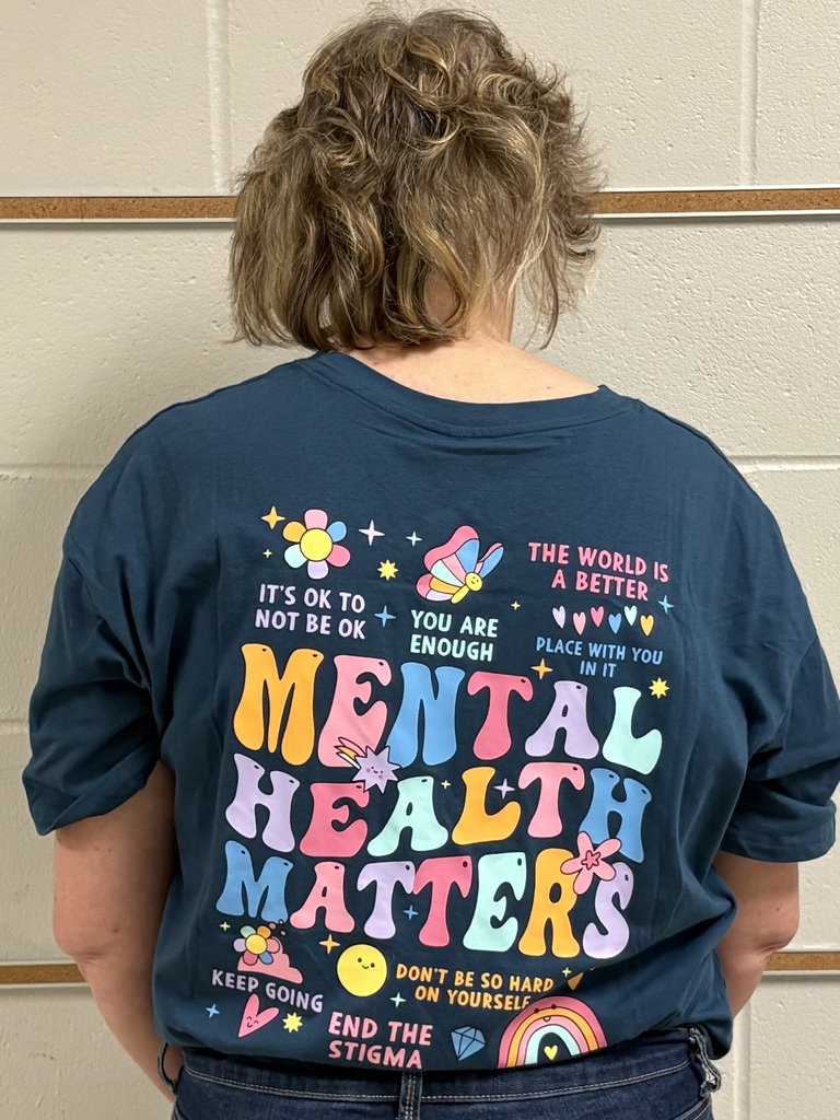 Back view of an educator wearing a colorful shirt reading “Mental Health Matters” surrounded by positive affirmations and icons.