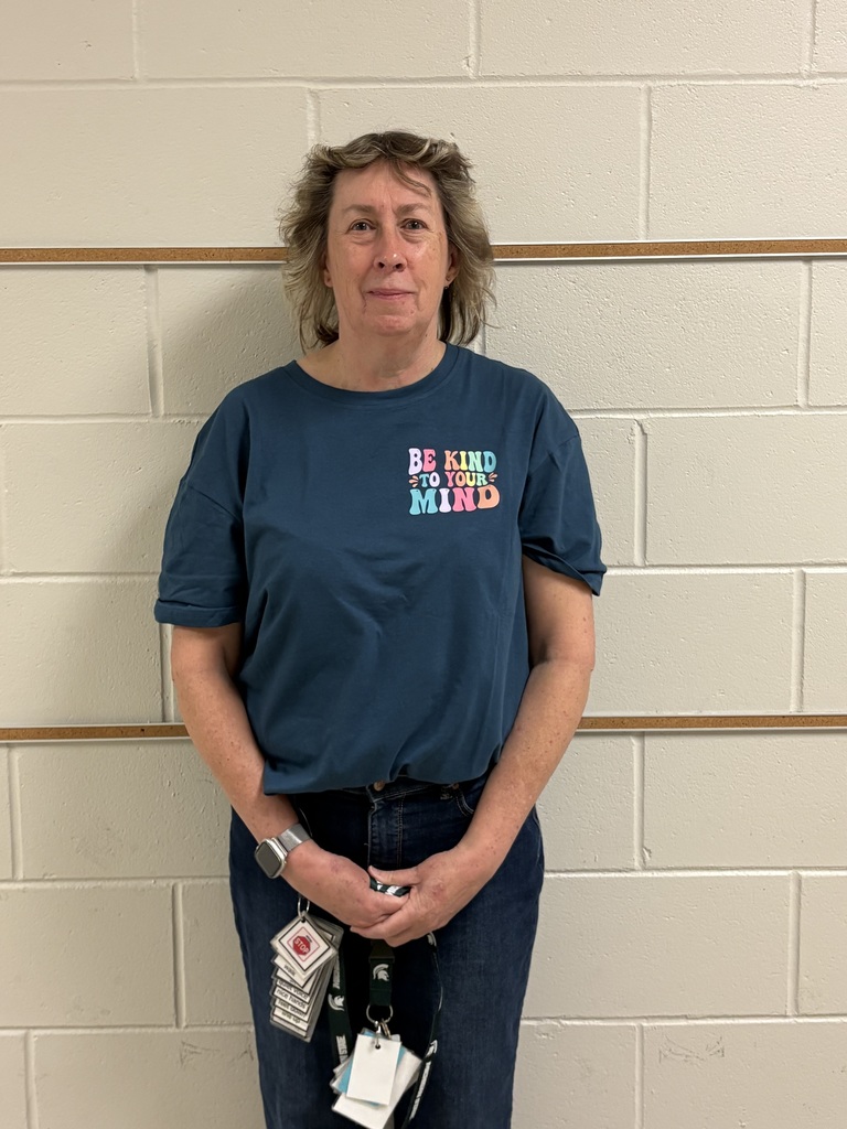An educator standing against a wall wearing a blue shirt that reads “Be Kind to Your Mind.”