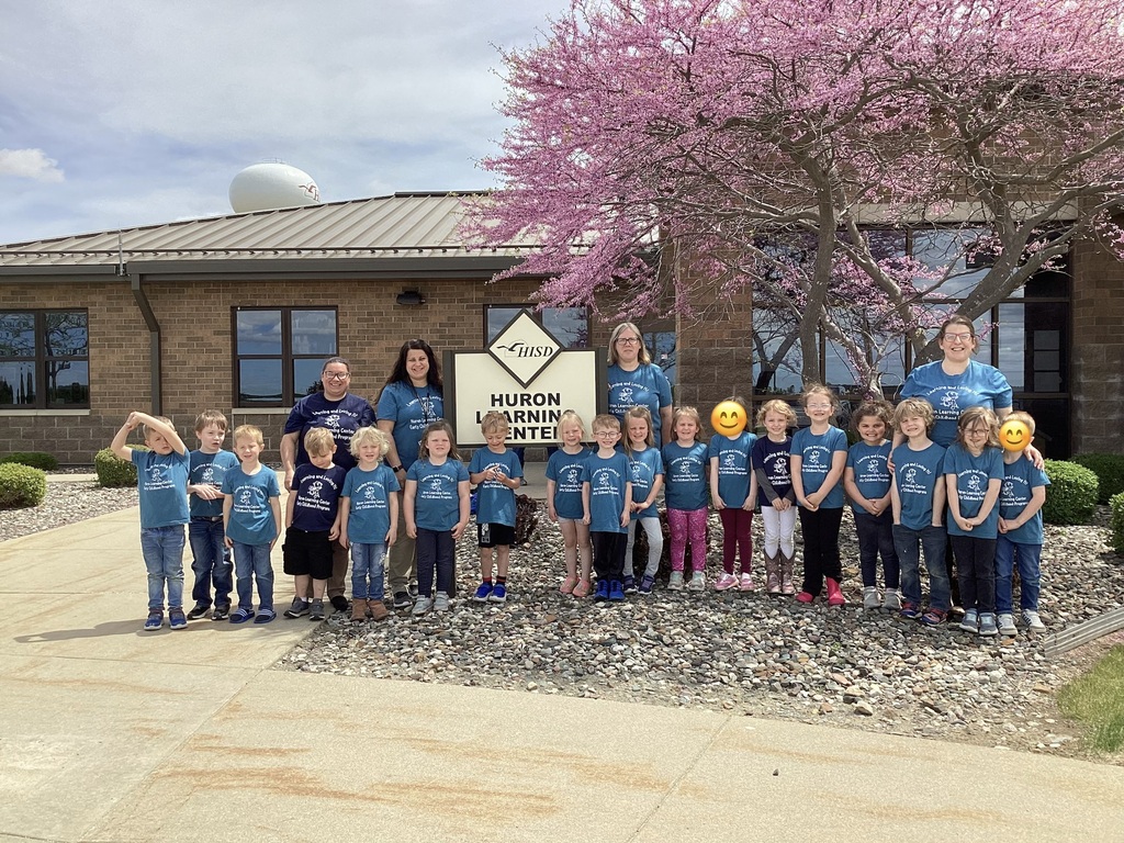 A group of preschool students and their teachers gather in front of the Huron Learning Center sign