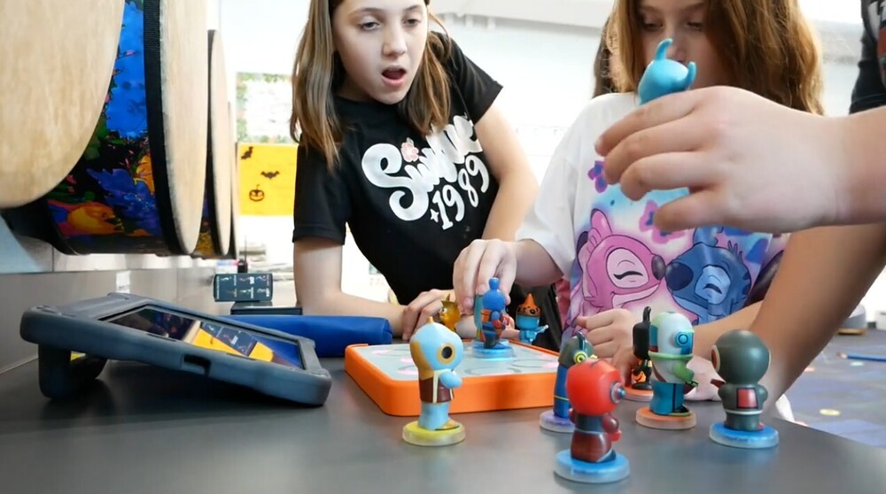 Photo of kids picking up figures and placing them on a soundboard loop lab to make music...