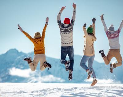 Young adults jumping in the air with excitement in a snowy scene