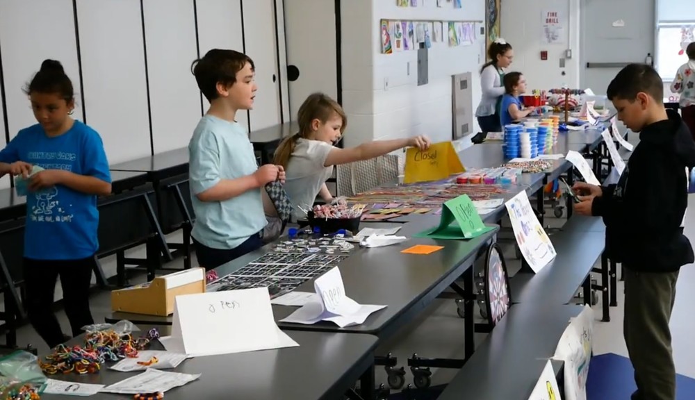 Image of students behind table "selling" items at mini Society day